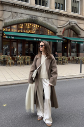 a lady wears a camel wrap coat with beige loose fit pants